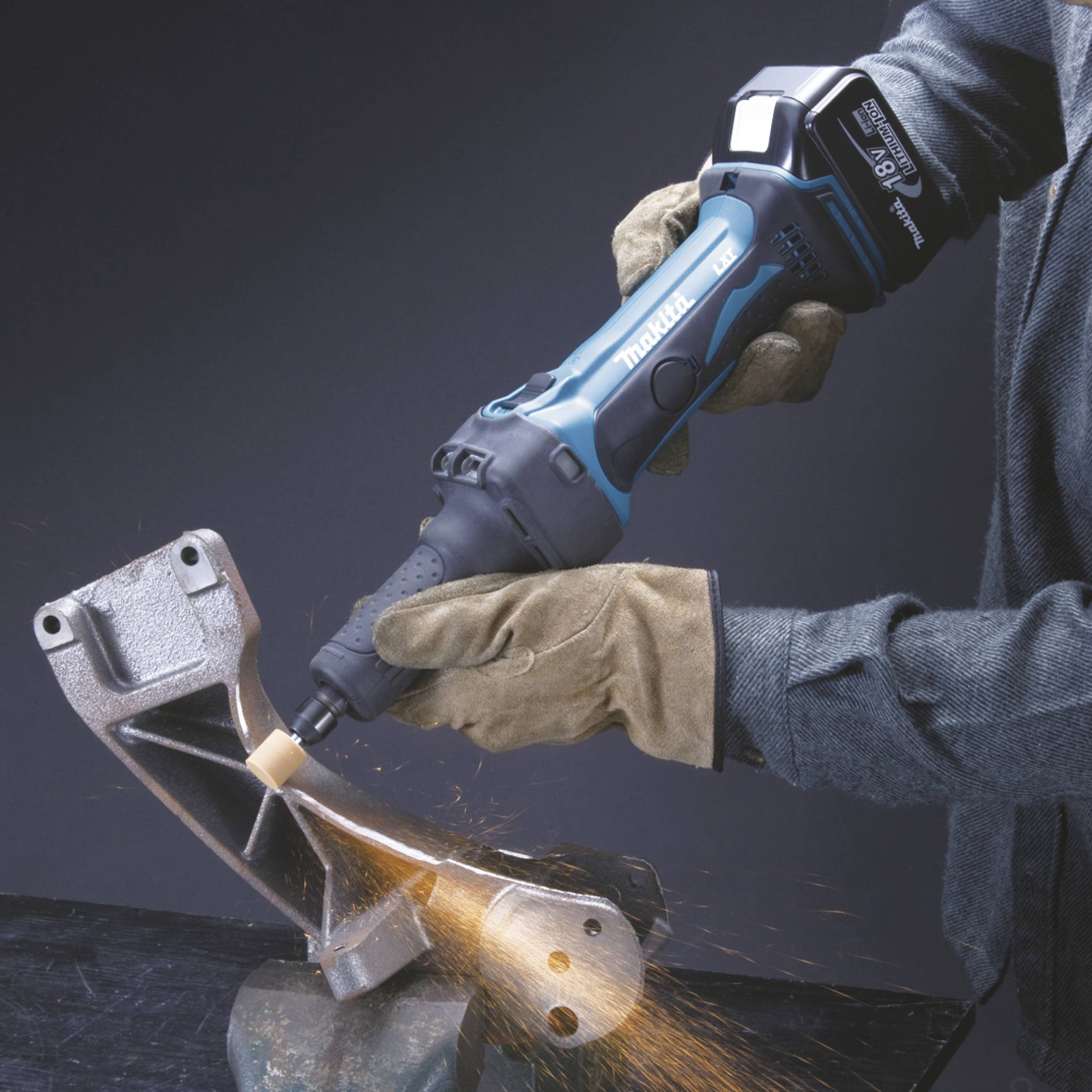 Une personne meule du métal dans un étau à l'aide d'une meuleuse d'angle, des étincelles volent. La personne porte des gants de travail.