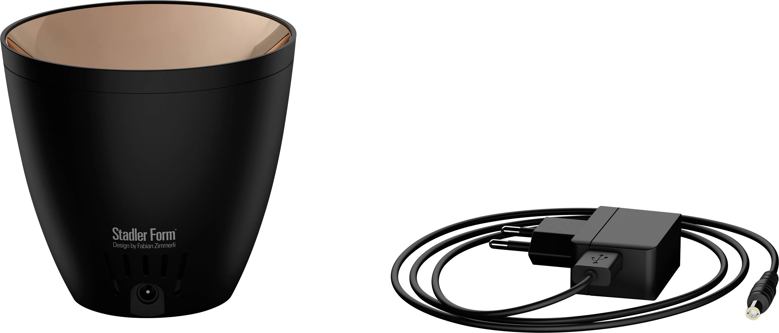 Un humidificateur noir de la marque Stadler Form avec un intérieur couleur cuivre, à côté duquel se trouve un adaptateur secteur assorti avec son câble.