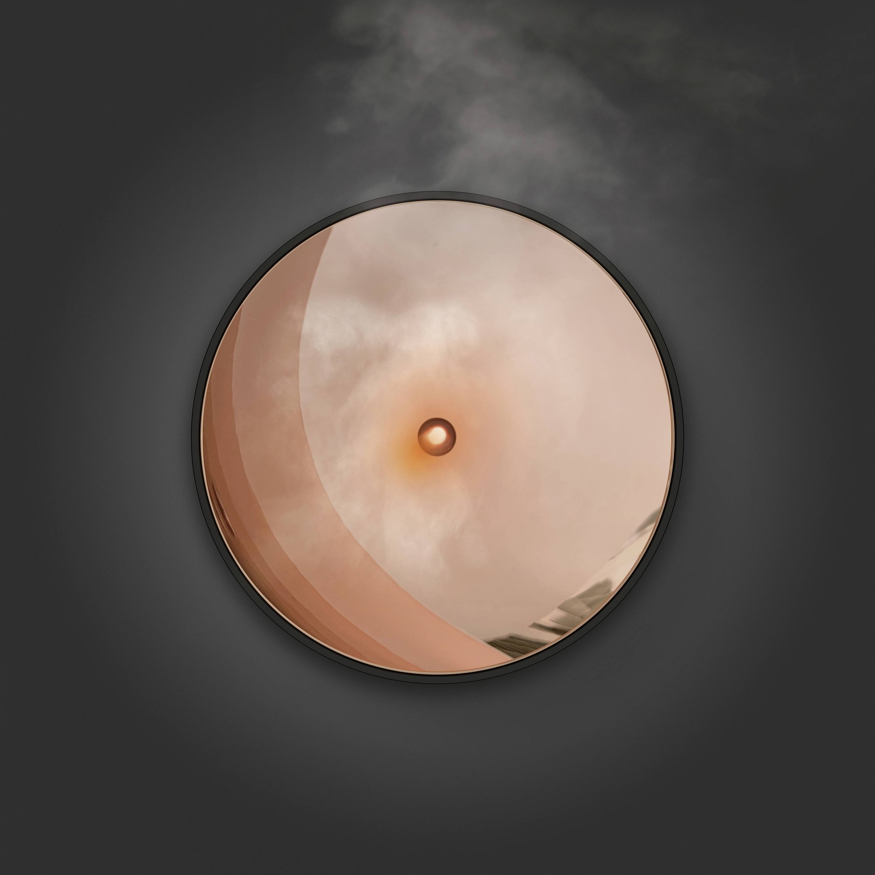 Un bouton ou interrupteur rond orange sur une surface sombre, légèrement entouré de fumée ou de brume.