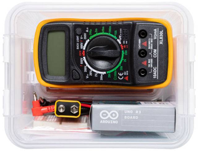 Un multimètre numérique dans un boîtier transparent, accompagné d'une carte Arduino et de câbles de mesure.