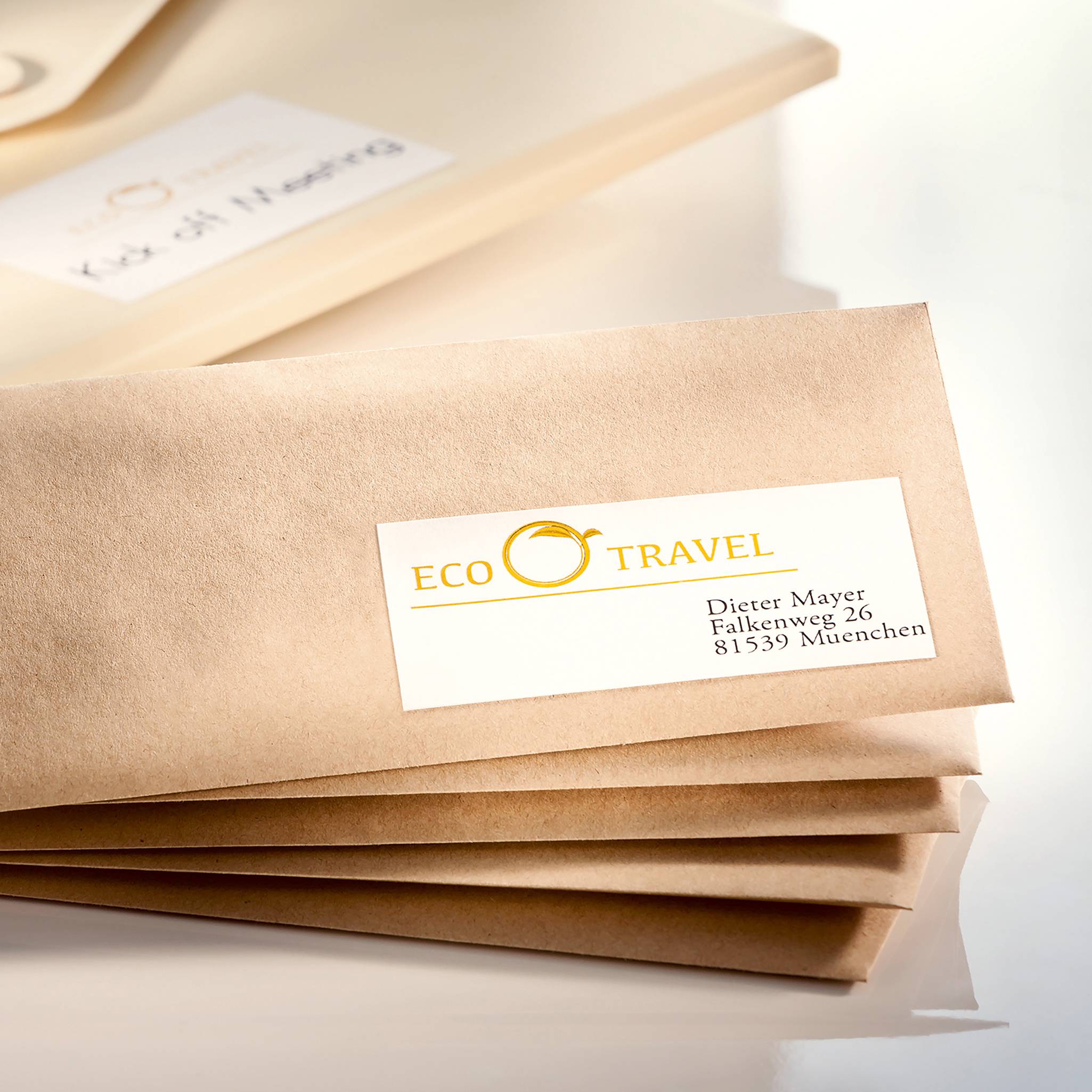 Une pochette marron avec une étiquette blanche de l'entreprise 'ECO TRAVEL', en dessous l'adresse : 'Dietmar Mayer, Kaiserstraße 23, 81539 Munich'.