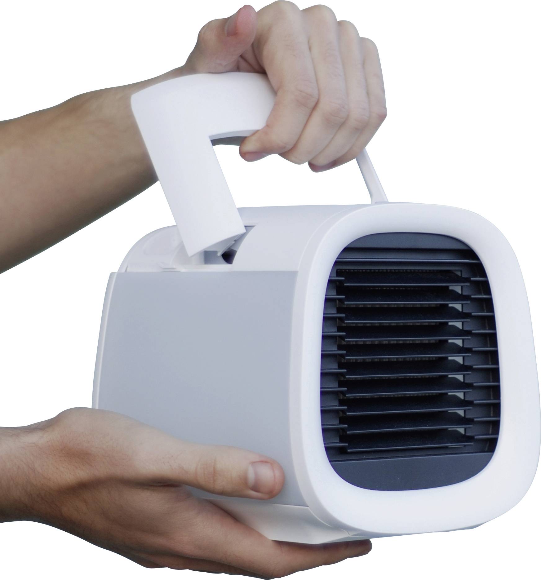Une personne tient un climatiseur portable blanc avec une poignée sur le dessus. L'appareil est orienté vers l'avant, et ses fentes de ventilation sont visibles.