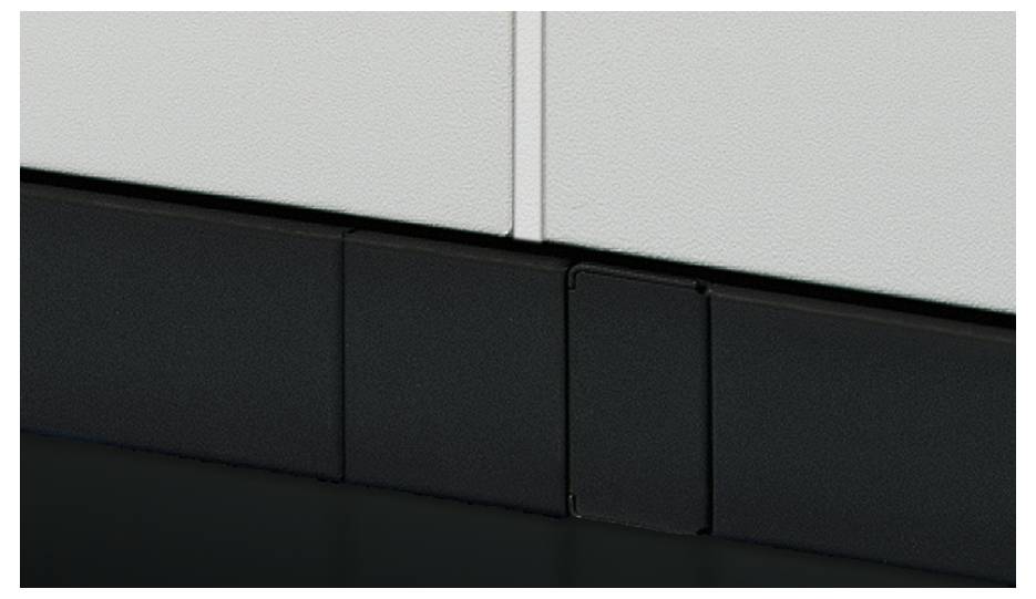 Plinthe de design moderne, gris foncé, à surface lisse, s'étendant parallèlement au mur à texture blanche, fixation sans joint.