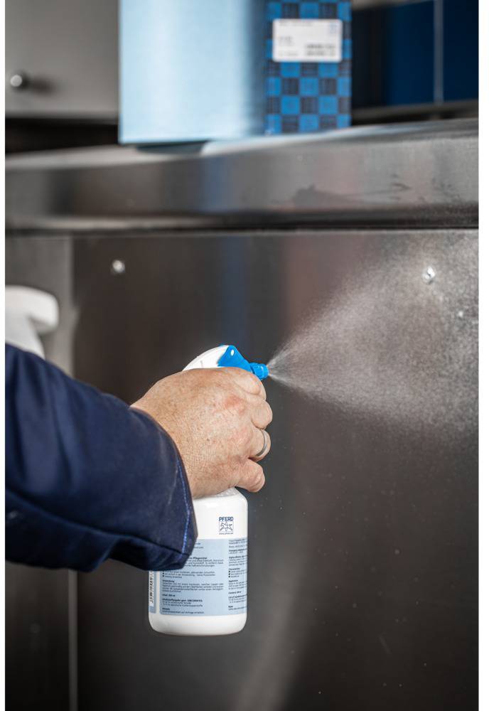 Une personne vaporise un spray nettoyant sur une surface métallique.