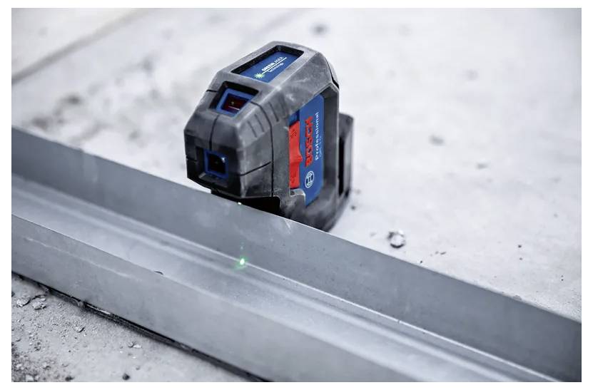 Un niveau laser projette un faisceau vert sur une surface métallique, utilisé pour des mesures précises dans les travaux de construction et les tâches d'alignement.