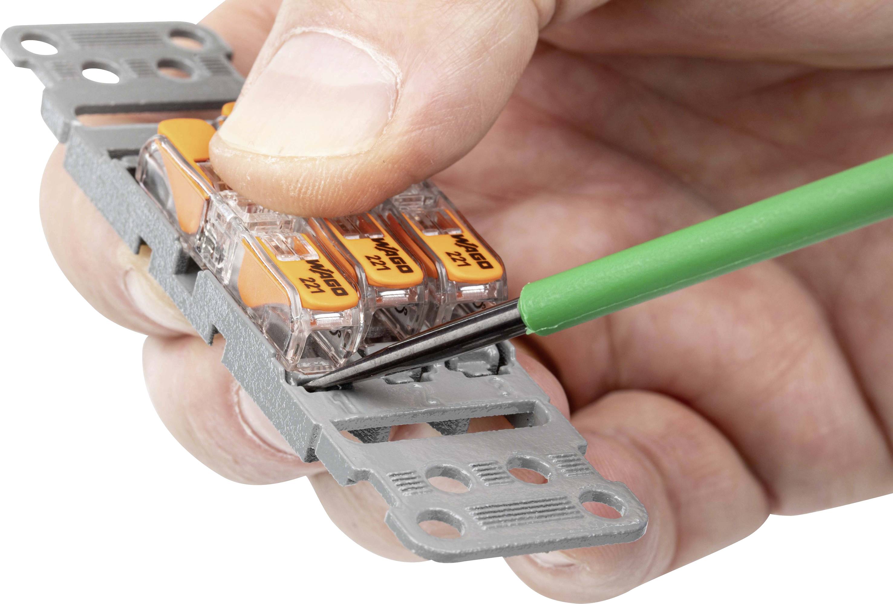 Un tournevis est utilisé pour desserrer un bornier de connexion Wago tenu dans une main.