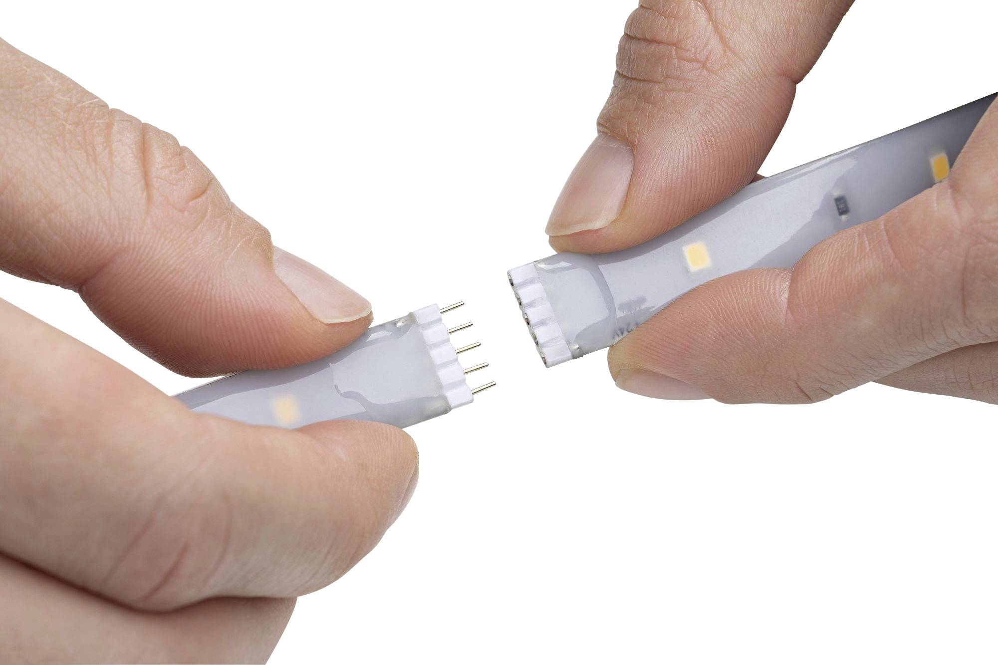Deux mains connectent deux parties d'une bande LED, avec des broches métalliques visibles servant de connecteurs.