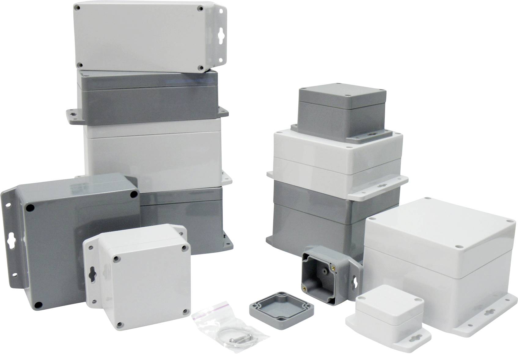 Plusieurs boîtiers en plastique gris et blancs de différentes tailles et formes, empilés et placés côte à côte sur un fond blanc.