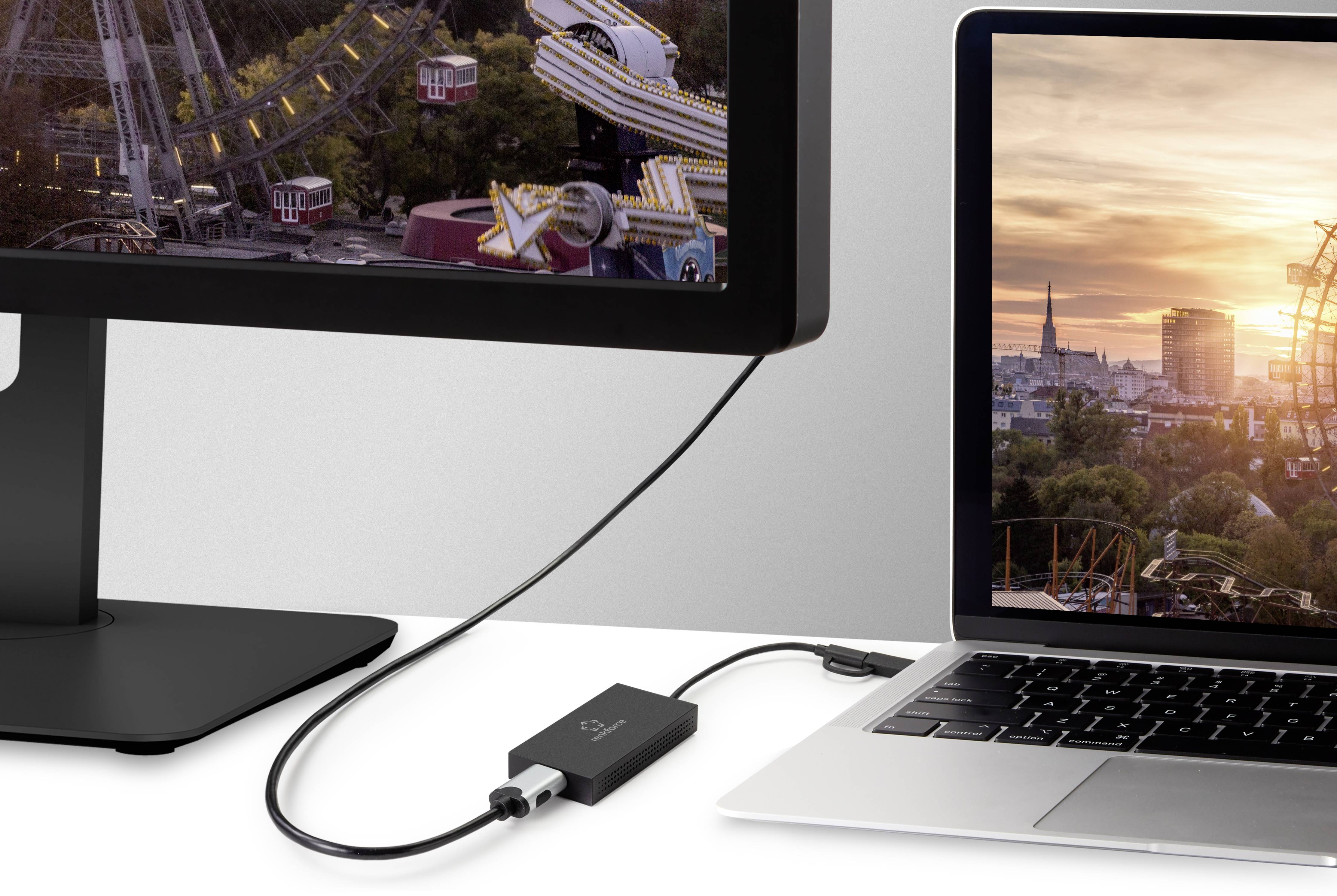 Un ordinateur portable est connecté à un moniteur. Un adaptateur est intercalé entre les deux. Le moniteur affiche une image d'une grande roue au coucher du soleil.