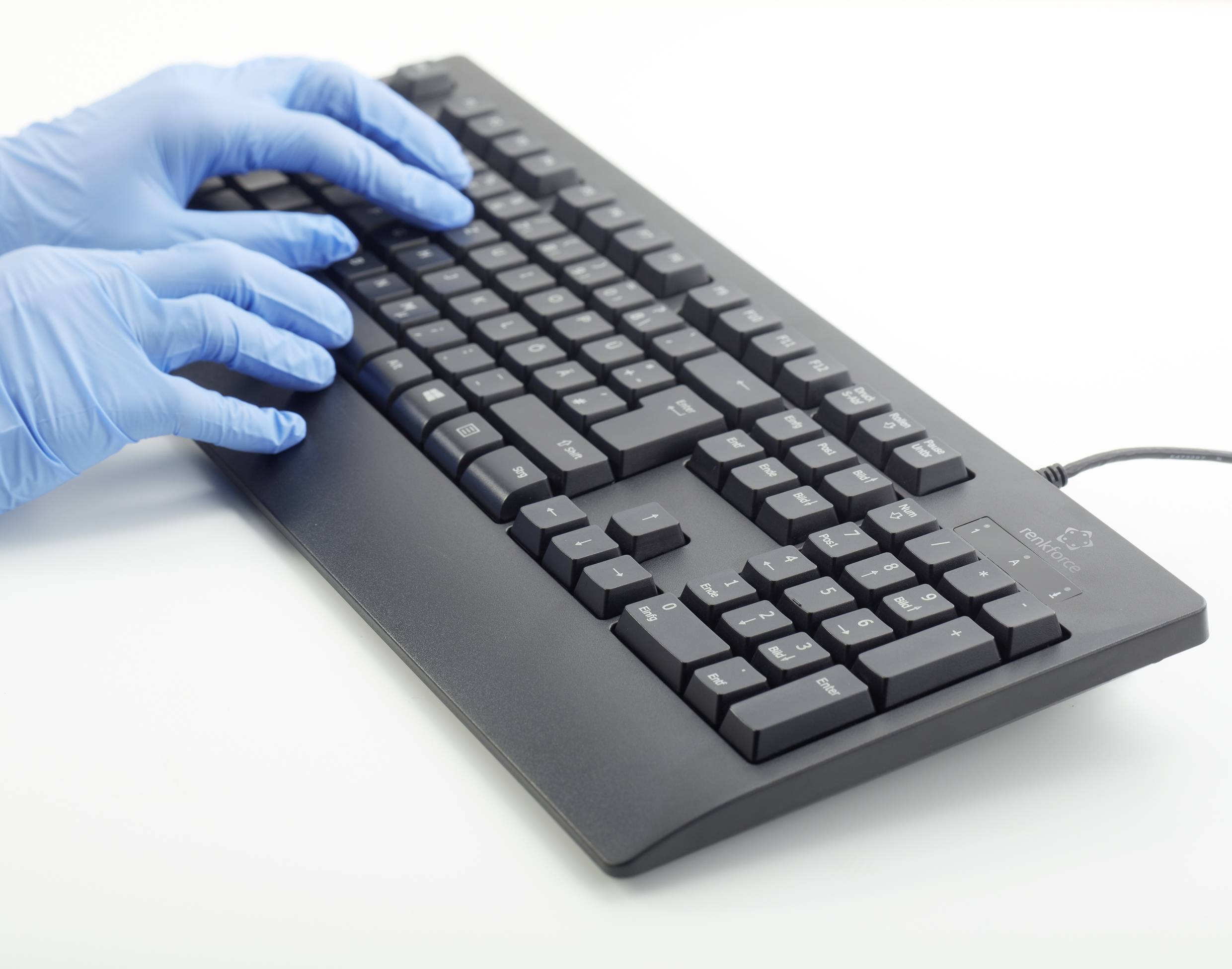 Des mains gantées de bleu en latex tapent sur un clavier d'ordinateur noir.