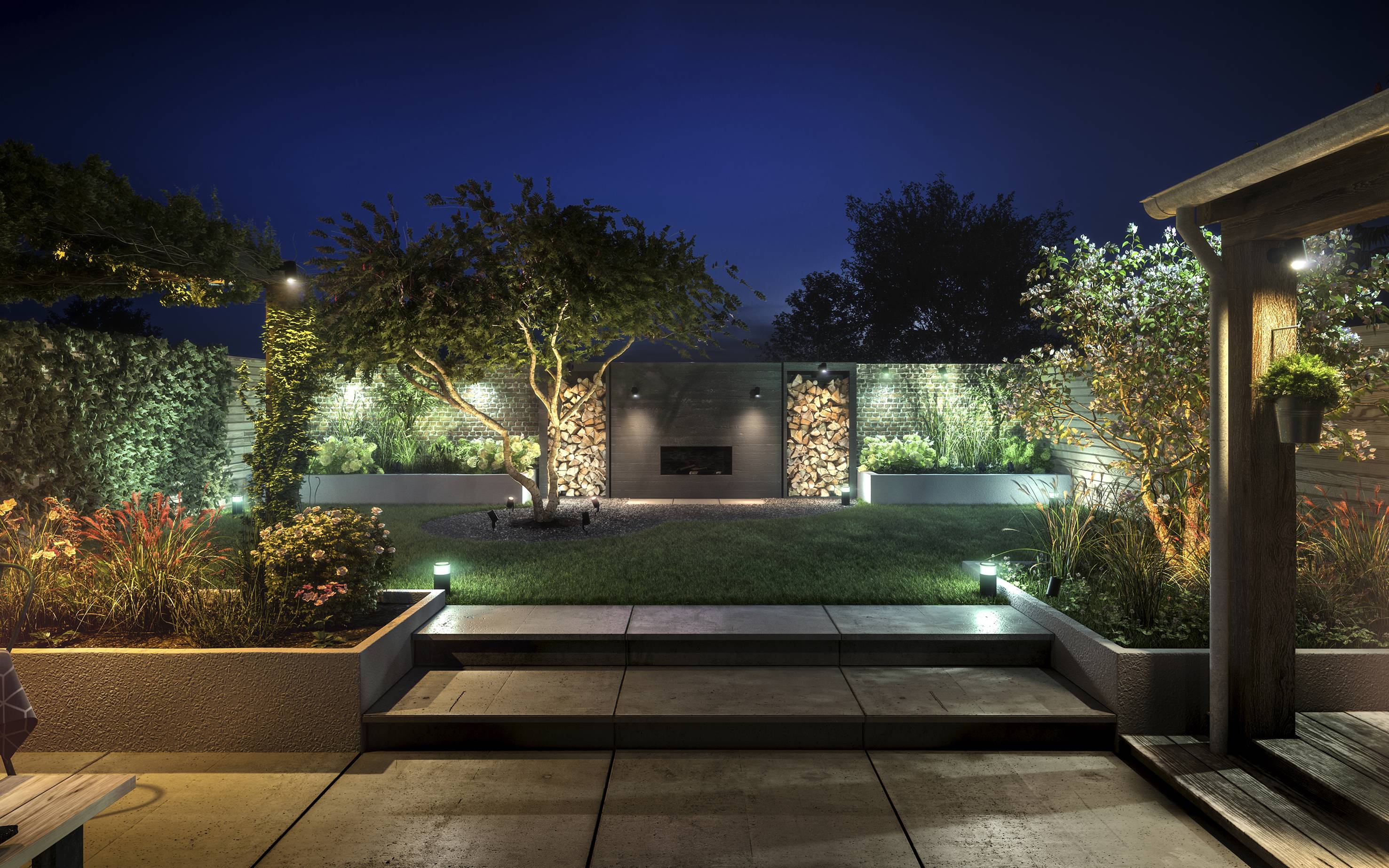 Un jardin éclairé la nuit avec des plantes soignées, un mur de pierre et un petit bassin d'eau au premier plan.