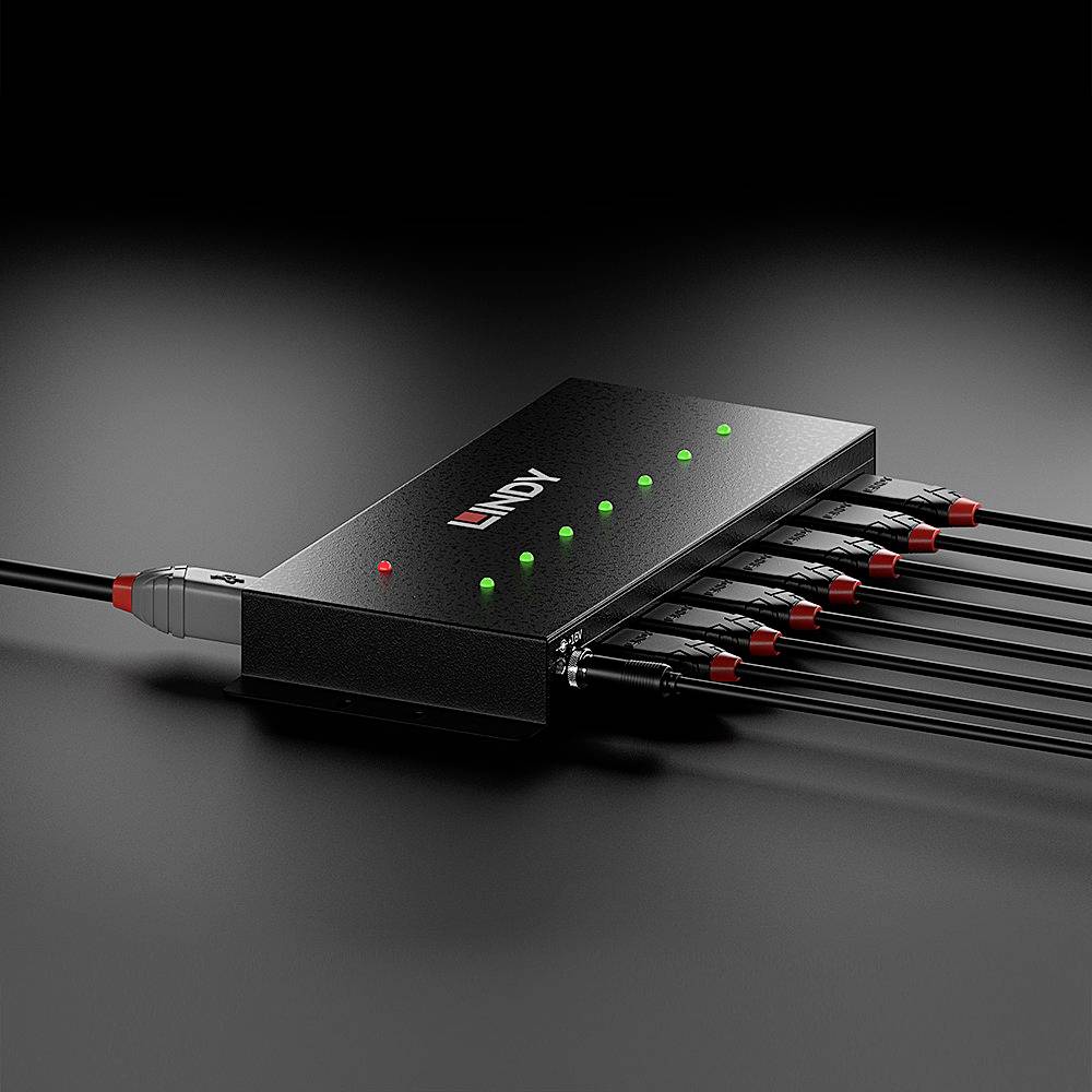 Un appareil électronique noir avec plusieurs câbles connectés et des LED vertes brillantes indiquant l'état de fonctionnement.