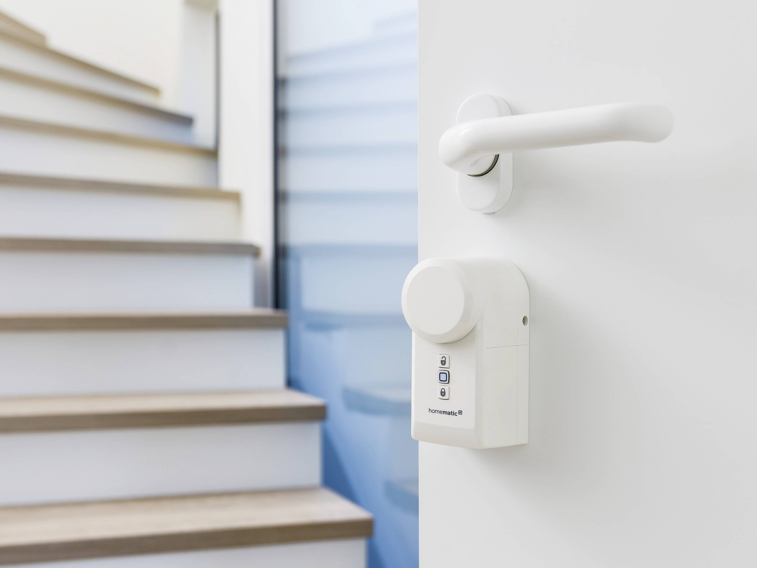Une porte blanche avec une serrure électronique au premier plan, avec un escalier en bois et des murs bleus en arrière-plan.