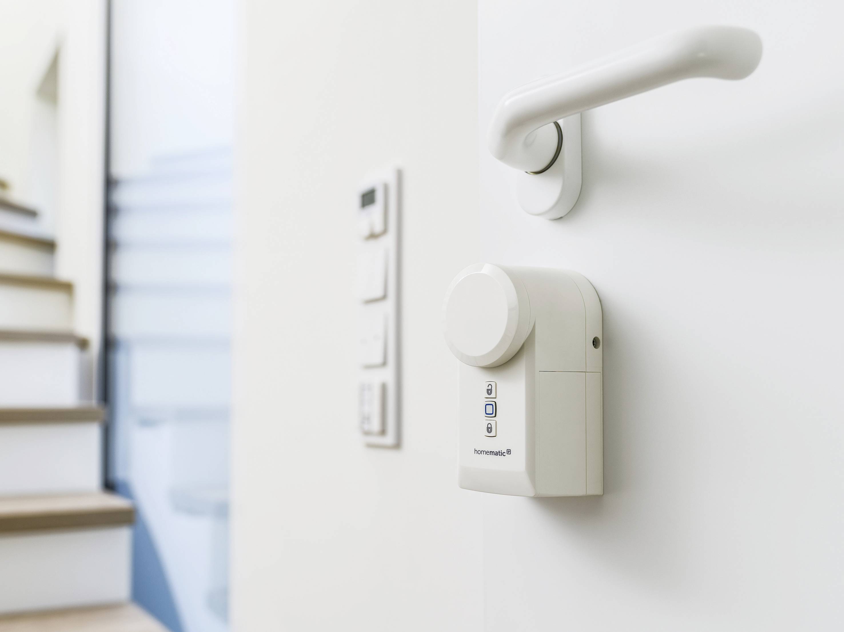 Serrure électronique intelligente sur une porte blanche, avec un escalier en arrière-plan.