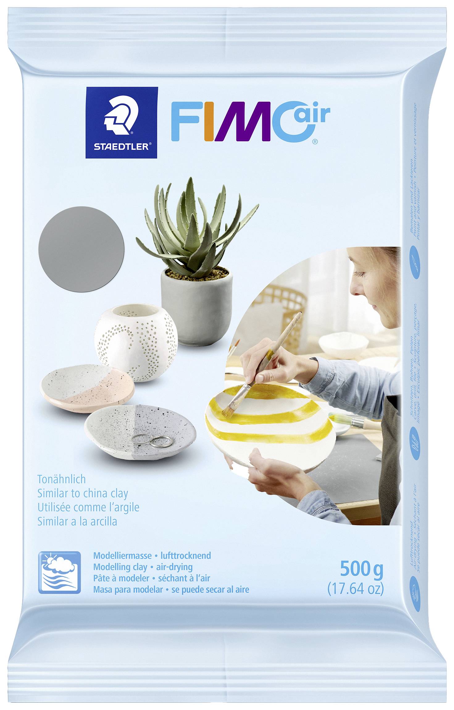 Masse à modeler semblable à l'argile 'FIMO air', paquet de 500 g, femme peignant de la céramique, plante en pot et bols décoratifs en arrière-plan.