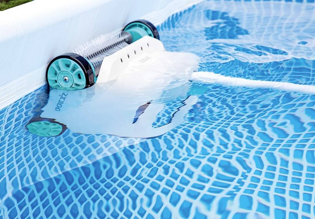 Un robot nettoyeur de piscine automatique se déplace à travers un bassin bleu et nettoie le fond des saletés et des dépôts.