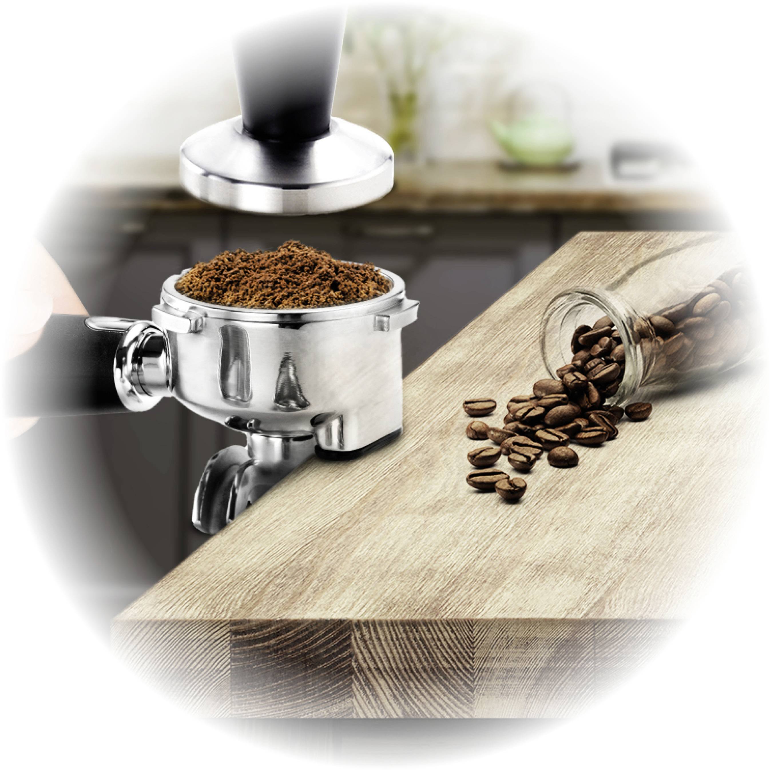 Un porte-filtre est rempli de café moulu et tassé, avec des grains de café et un coin cuisine visibles en arrière-plan.