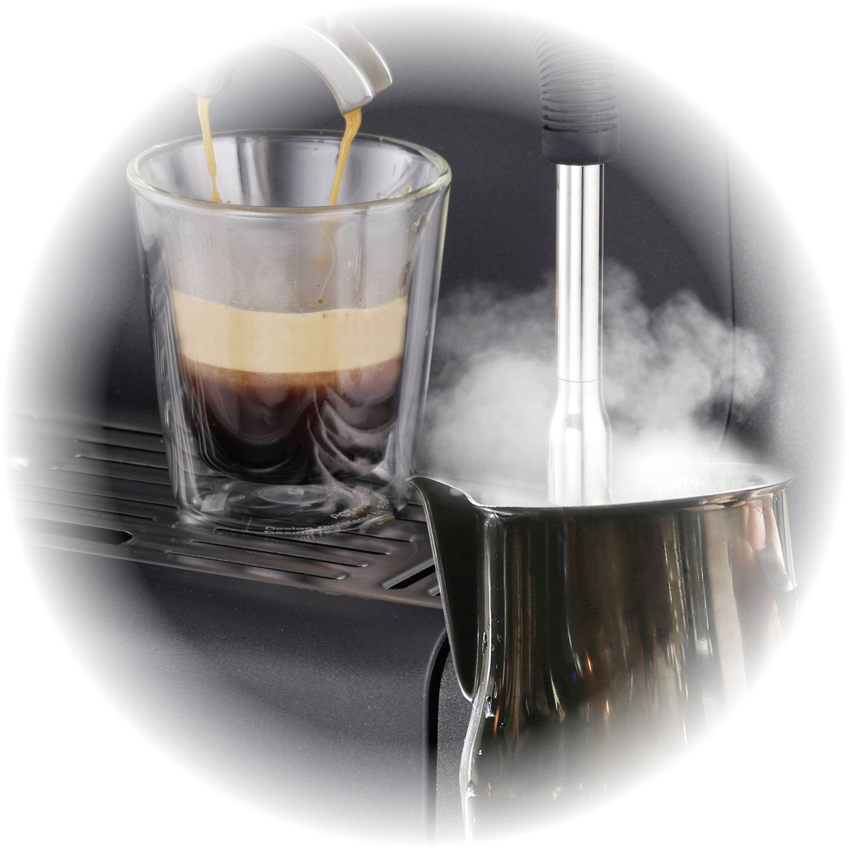 Un verre rempli d'espresso fraîchement préparé est posé, à côté duquel une cruche de lait dégage de la vapeur.