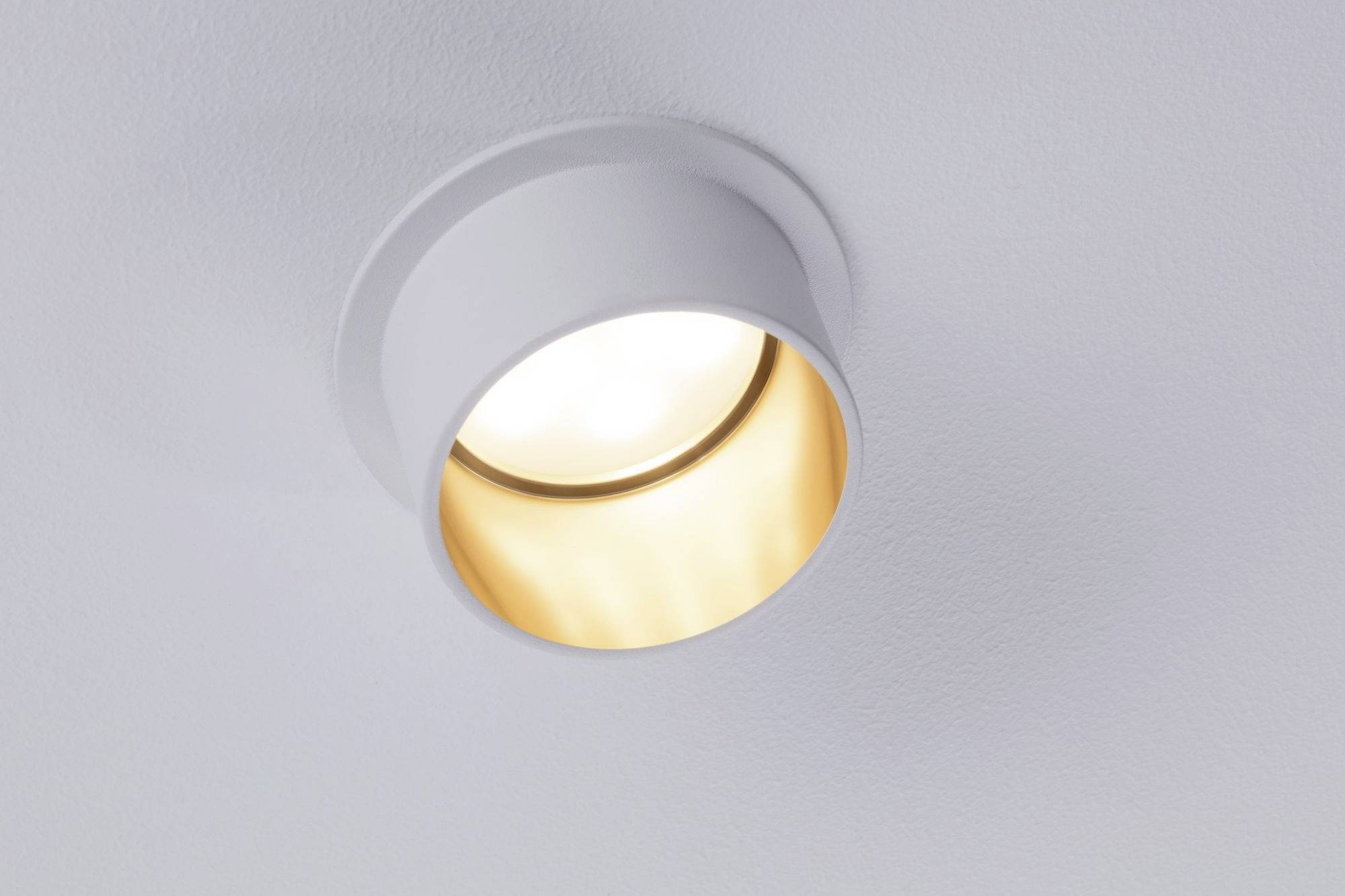 Une applique ronde diffuse une lumière chaleureuse, fixée au plafond blanc.