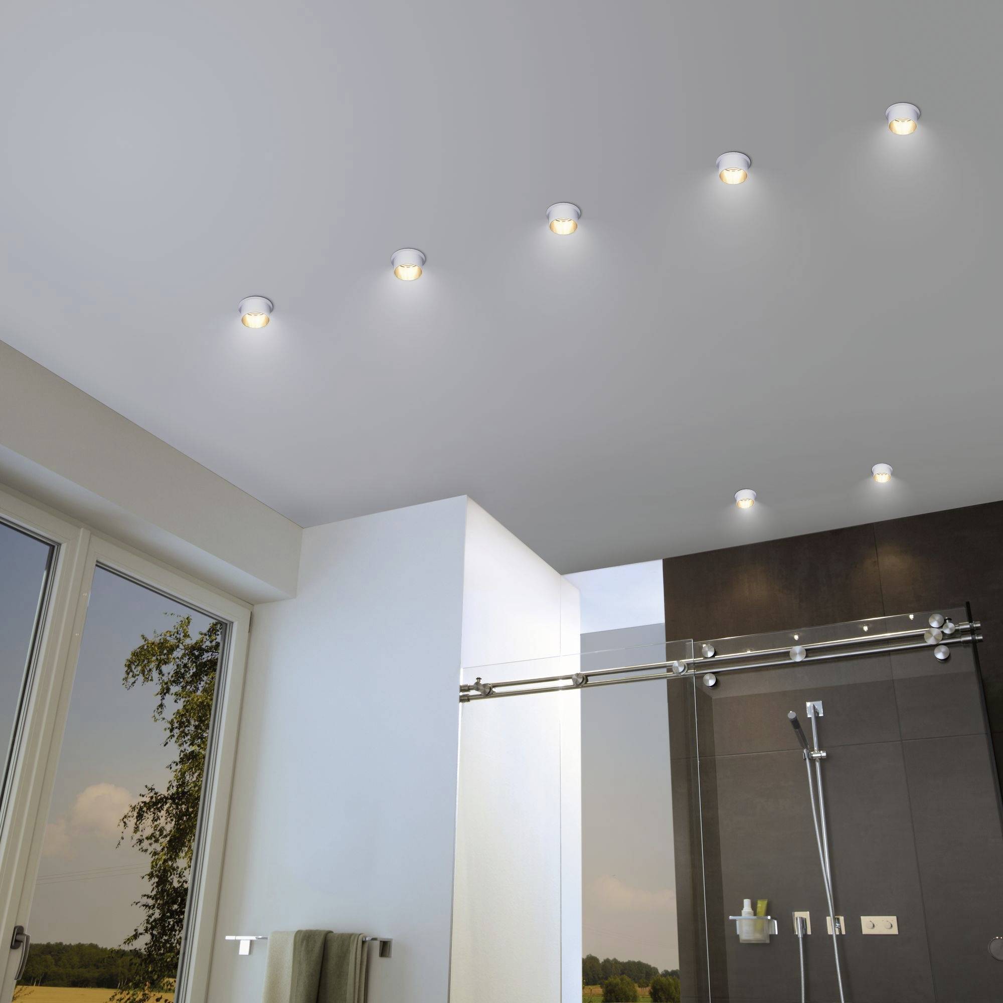 Plafond de salle de bain moderne avec plusieurs spots encastrés circulaires, en dessous une douche et une fenêtre donnant sur l'extérieur.