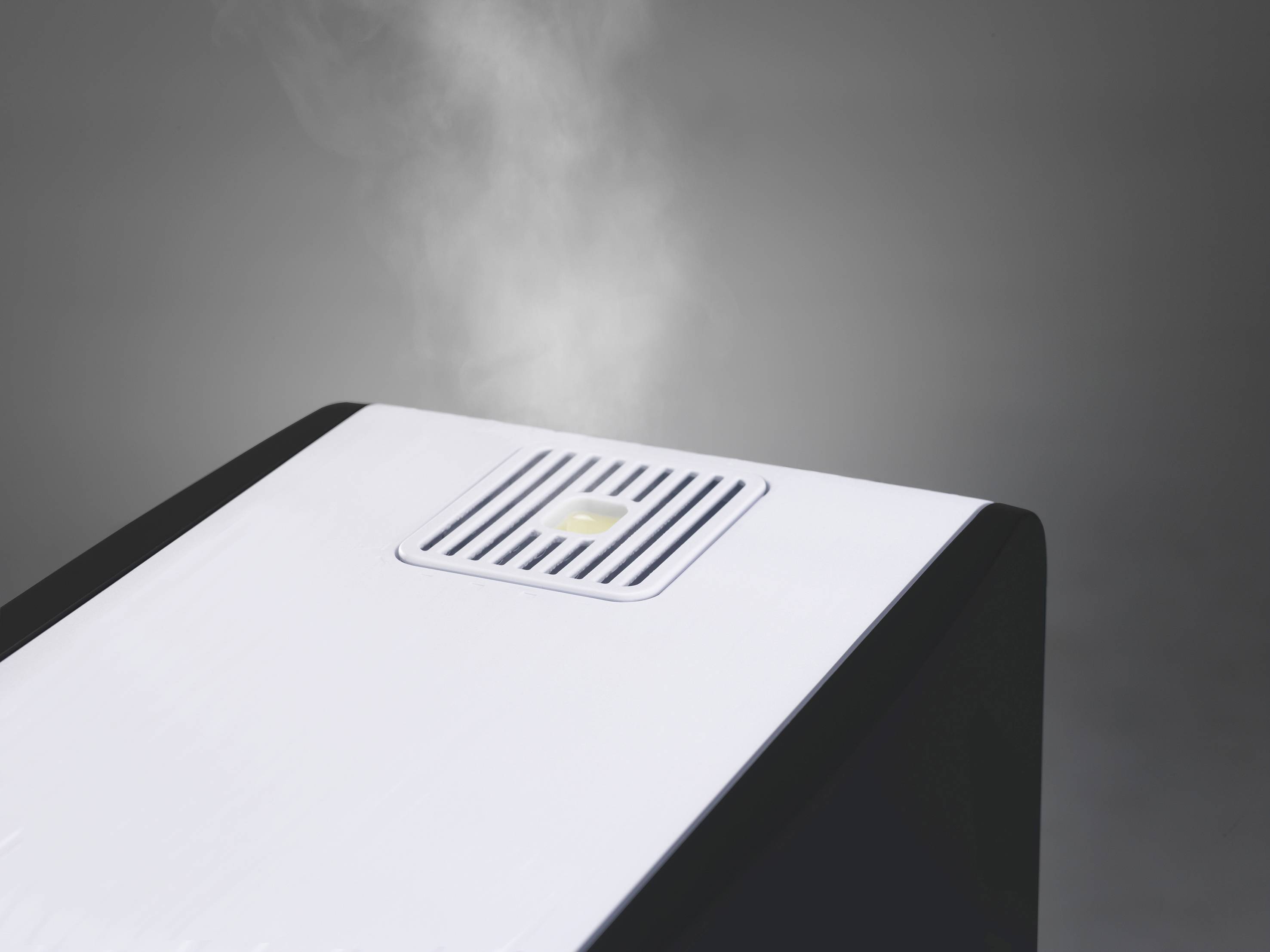 Un humidificateur d'air, avec de la vapeur s'élevant, sur un fond gris.