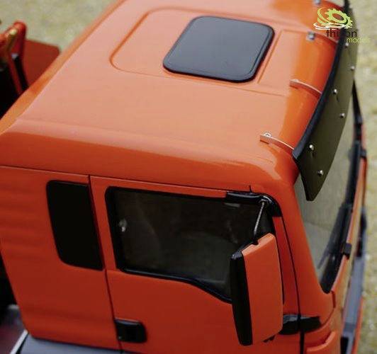 Camion miniature rouge vu de dessus, montrant la cabine du conducteur avec des fenêtres et des rétroviseurs détaillés, sur un fond beige.