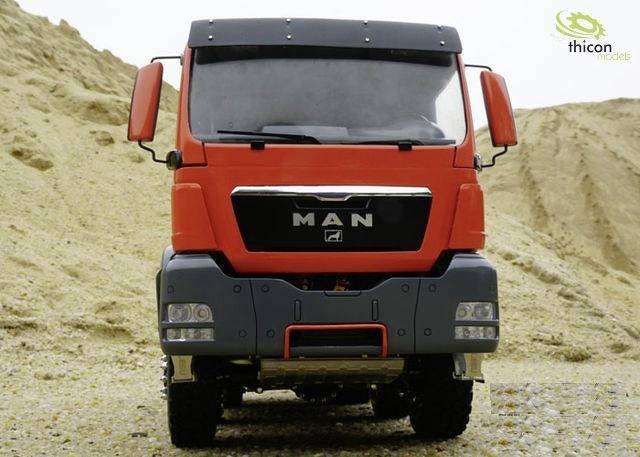 Un camion rouge est stationné devant un fond de dunes de sable. Sur la face avant est inscrit 'MAN'. Le logo de Thicon Modelle est situé en haut à droite.