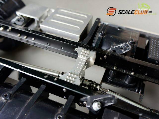 Gros plan d'un châssis de véhicule miniature avec des pièces en métal et en plastique. Les logos de 'Scaleclub' et 'Techicon' sont visibles en haut.