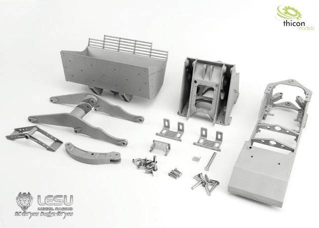 Pièces d'un véhicule miniature en métal, comprenant le châssis, la suspension et d'autres petits composants, disposées sur une surface blanche.