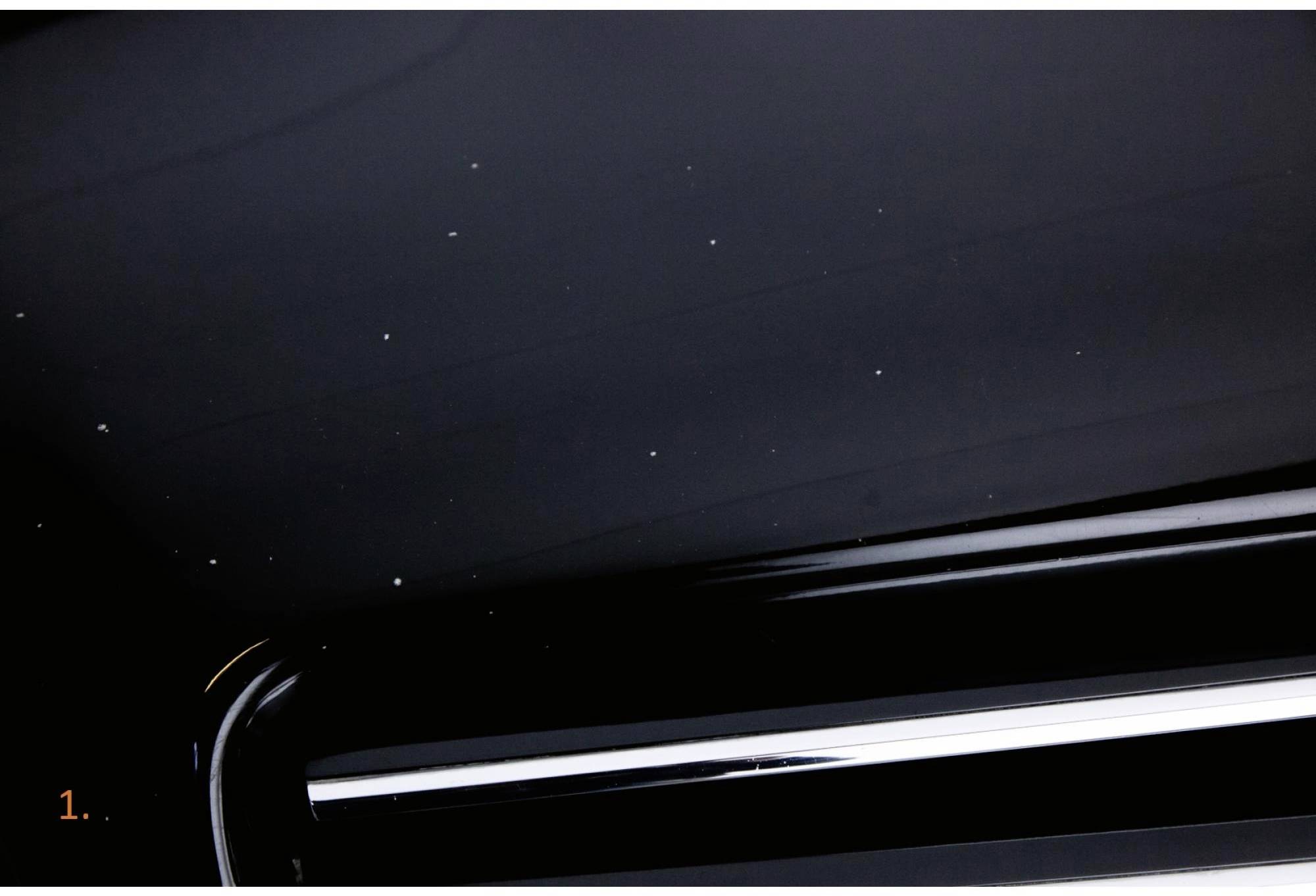 Gros plan sur une surface noire brillante présentant des taches blanches et une structure horizontale dans la partie inférieure.