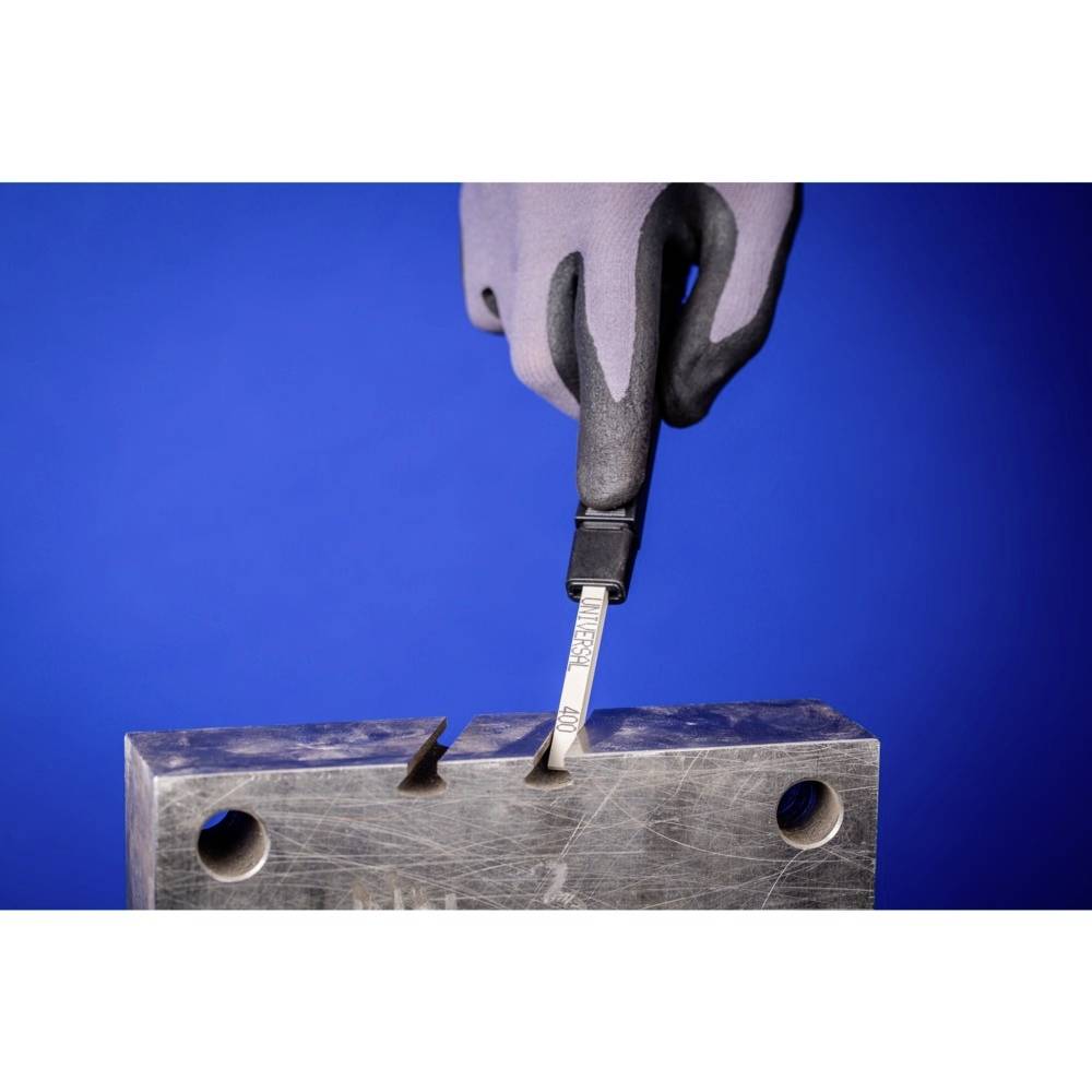 Une main gantée utilise un instrument de mesure pour vérifier une encoche dans un bloc métallique, sur un fond bleu.