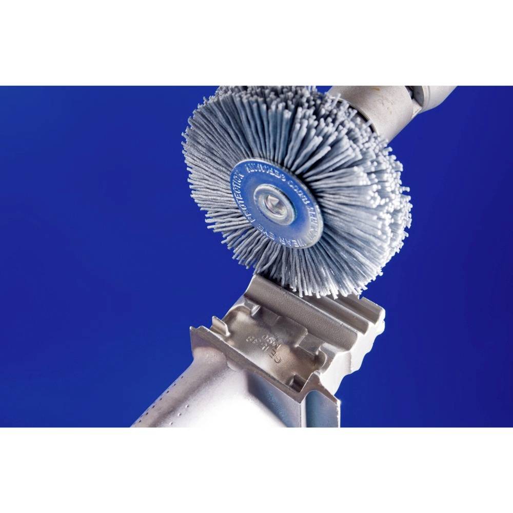 Une brosse métallique sur une meuleuse d'angle nettoie une surface métallique sur un fond bleu.