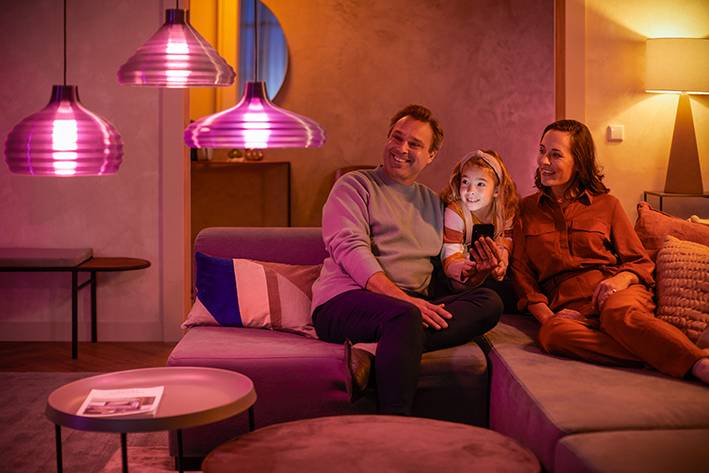 Une famille est confortablement installée sur le canapé le soir dans un salon à l'éclairage chaleureux.