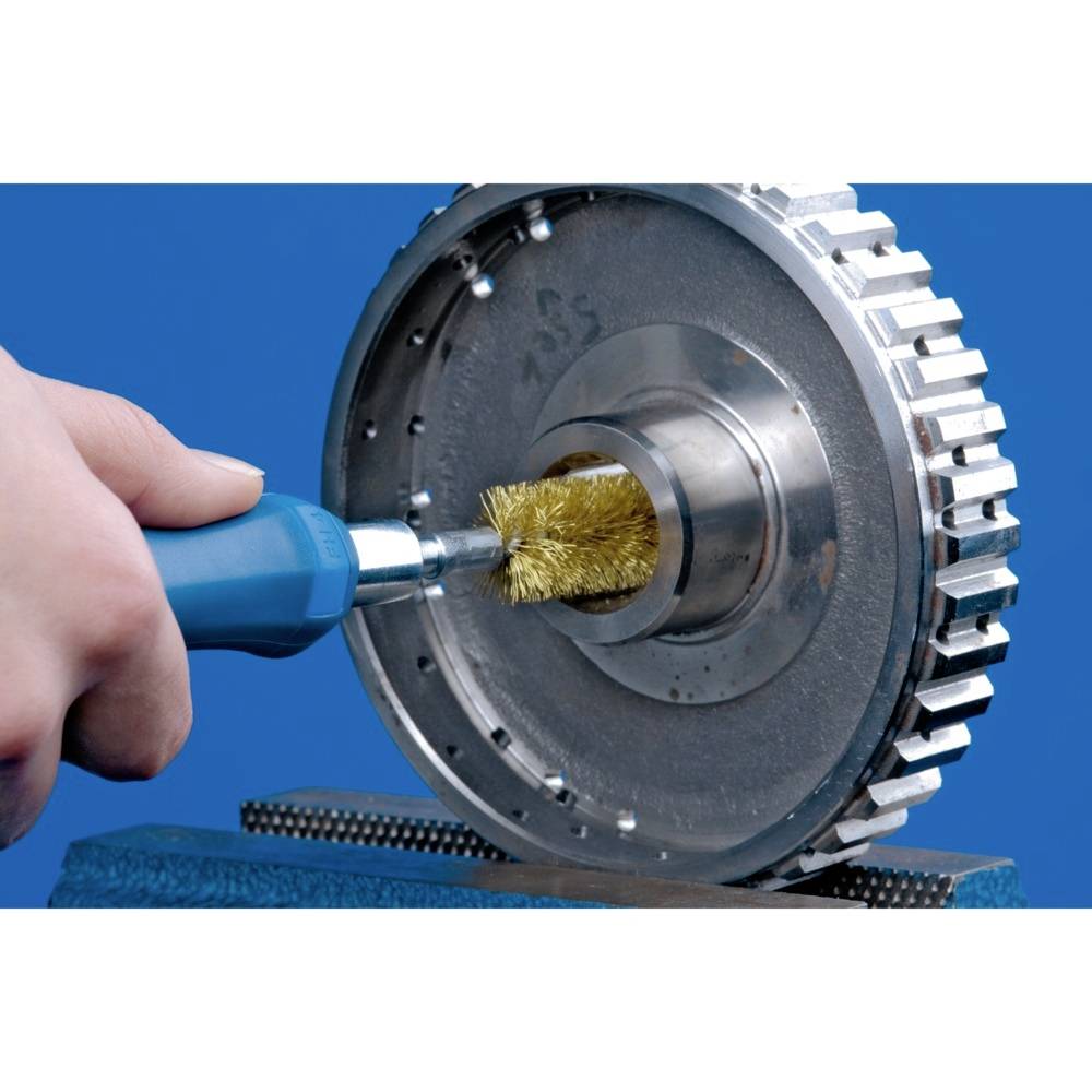 Une main tient un outil avec une brosse métallique qui nettoie une pièce métallique ressemblant à un engrenage. L'arrière-plan est bleu.