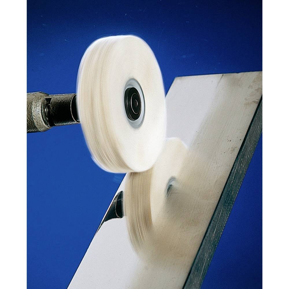 Un disque de polissage rotatif polit une surface métallique, créant un lustre brillant sur le métal contre un fond bleu.