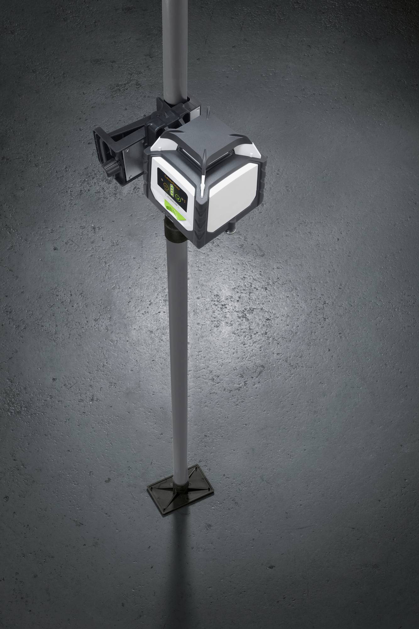 Un appareil de nivellement laser est fixé sur un trépied. Il s'illumine et projette un faisceau laser vert verticalement sur le sol.