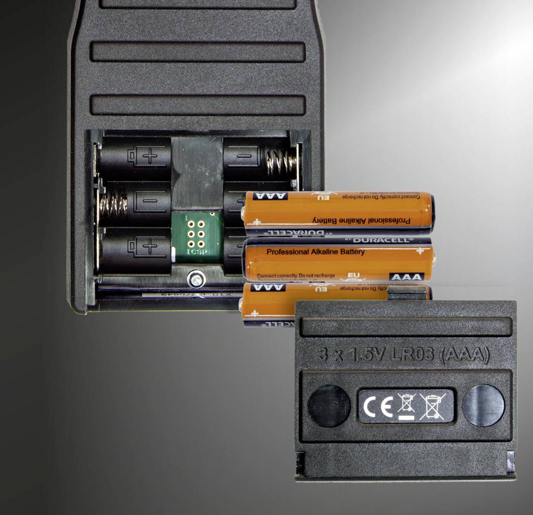Couvercle du compartiment à piles ouvert montrant trois piles AAA. Texte sur le couvercle : « 3 x 1,5V LR03 (AAA) » et symboles de sécurité.
