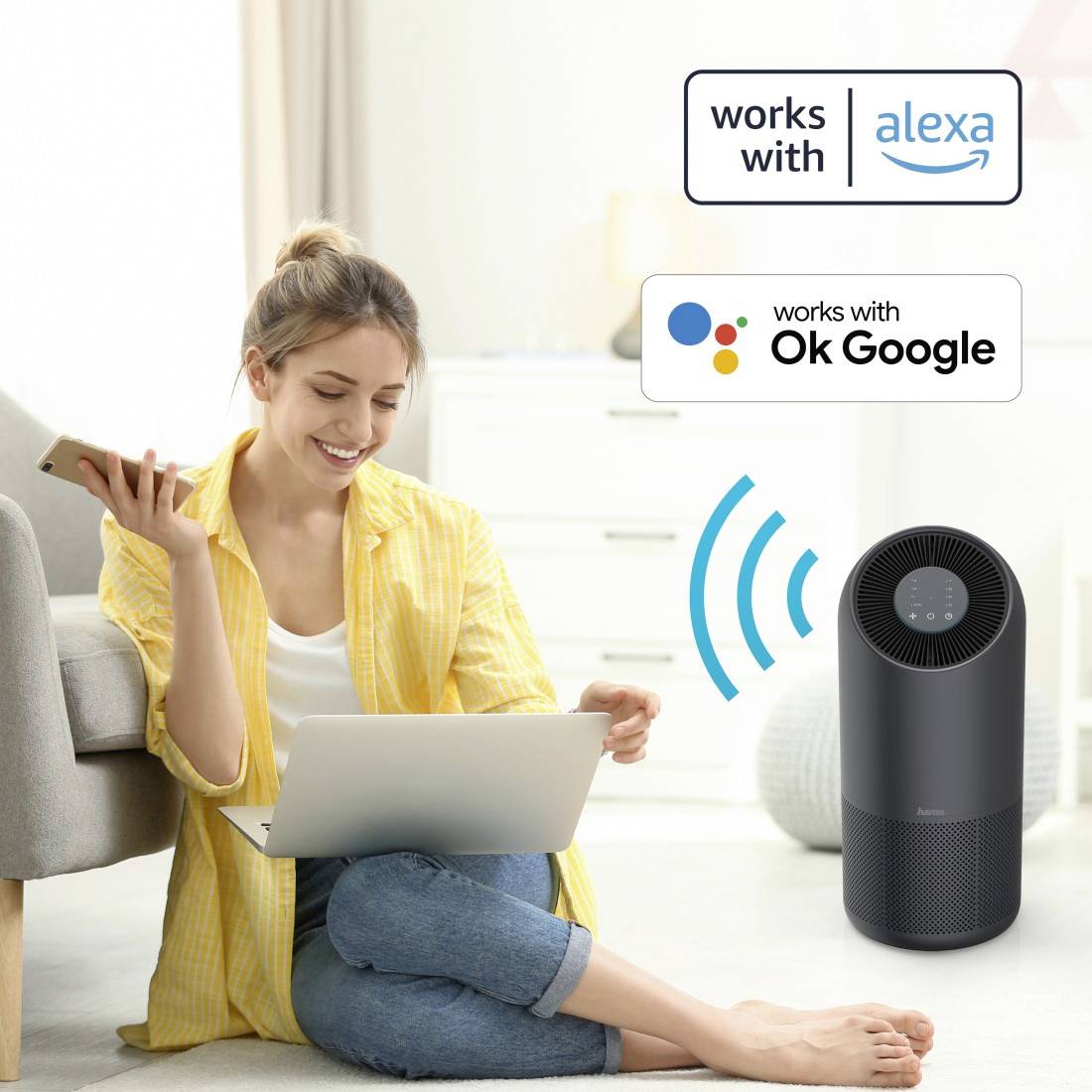 Une femme est assise souriante sur un canapé avec un ordinateur portable, à côté d'un haut-parleur intelligent. Des symboles indiquent la compatibilité avec 'Alexa' et 'Google Assistant'.