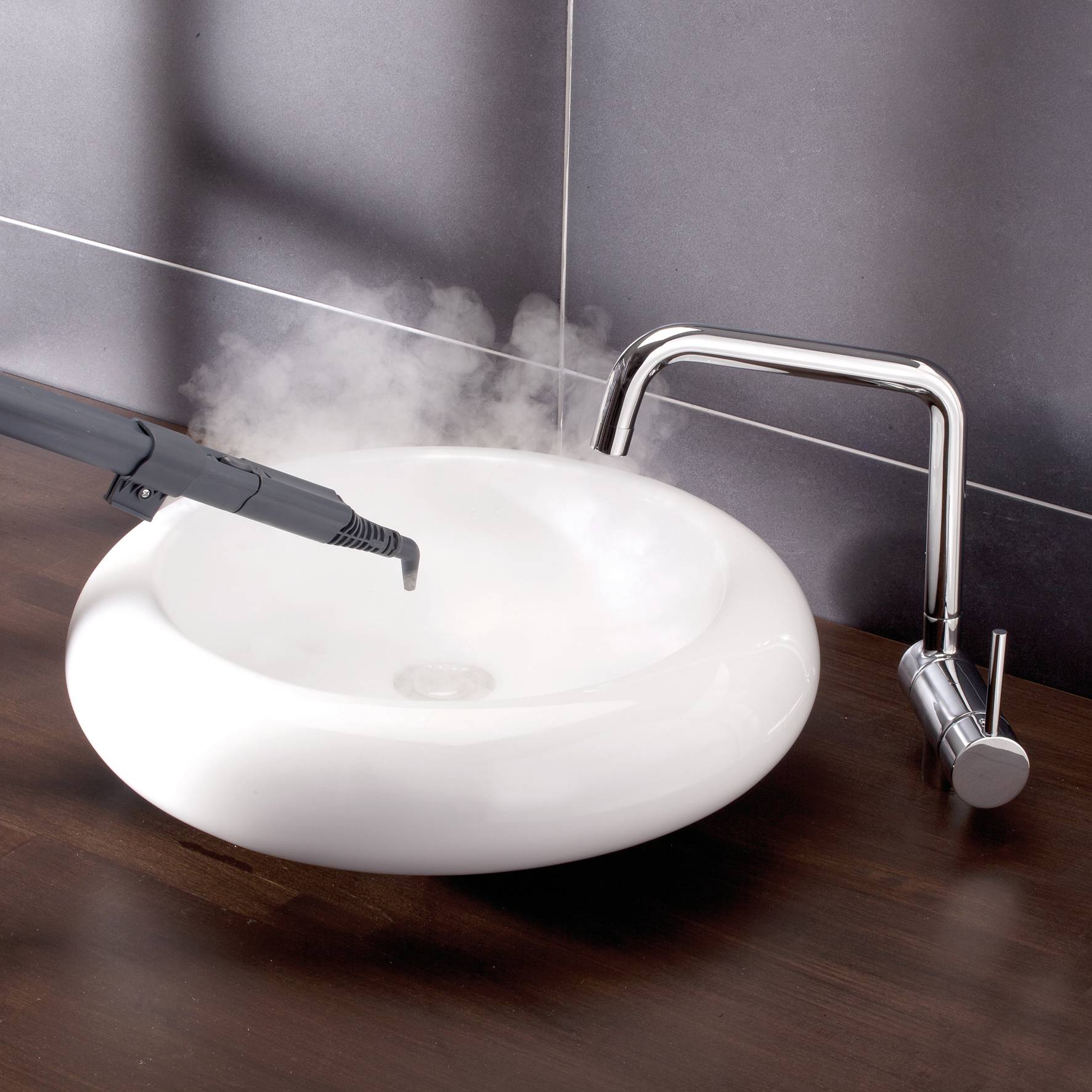 Un nettoyeur vapeur est dirigé vers un lavabo blanc, avec de la vapeur s'élevant au-dessus du lavabo ; l'accent est mis sur le nettoyage.
