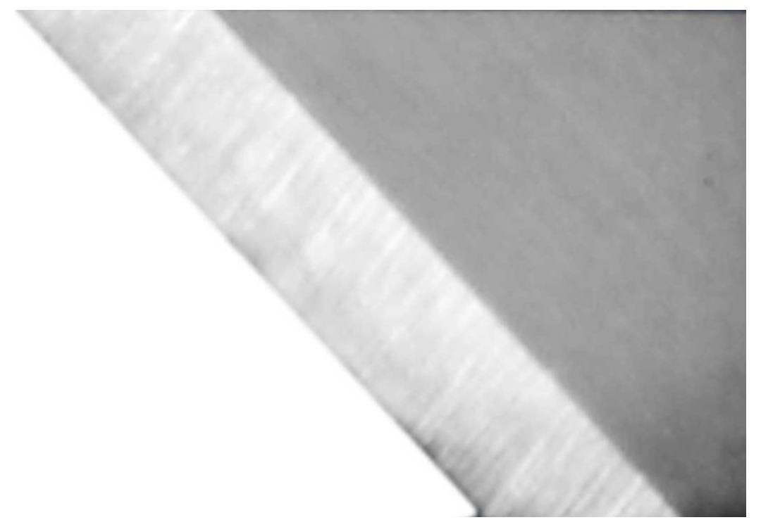 Photo noir et blanc d'un bord métallique, s'étendant en diagonale du coin inférieur gauche vers le coin supérieur droit. Un côté apparaît plus clair que l'autre.