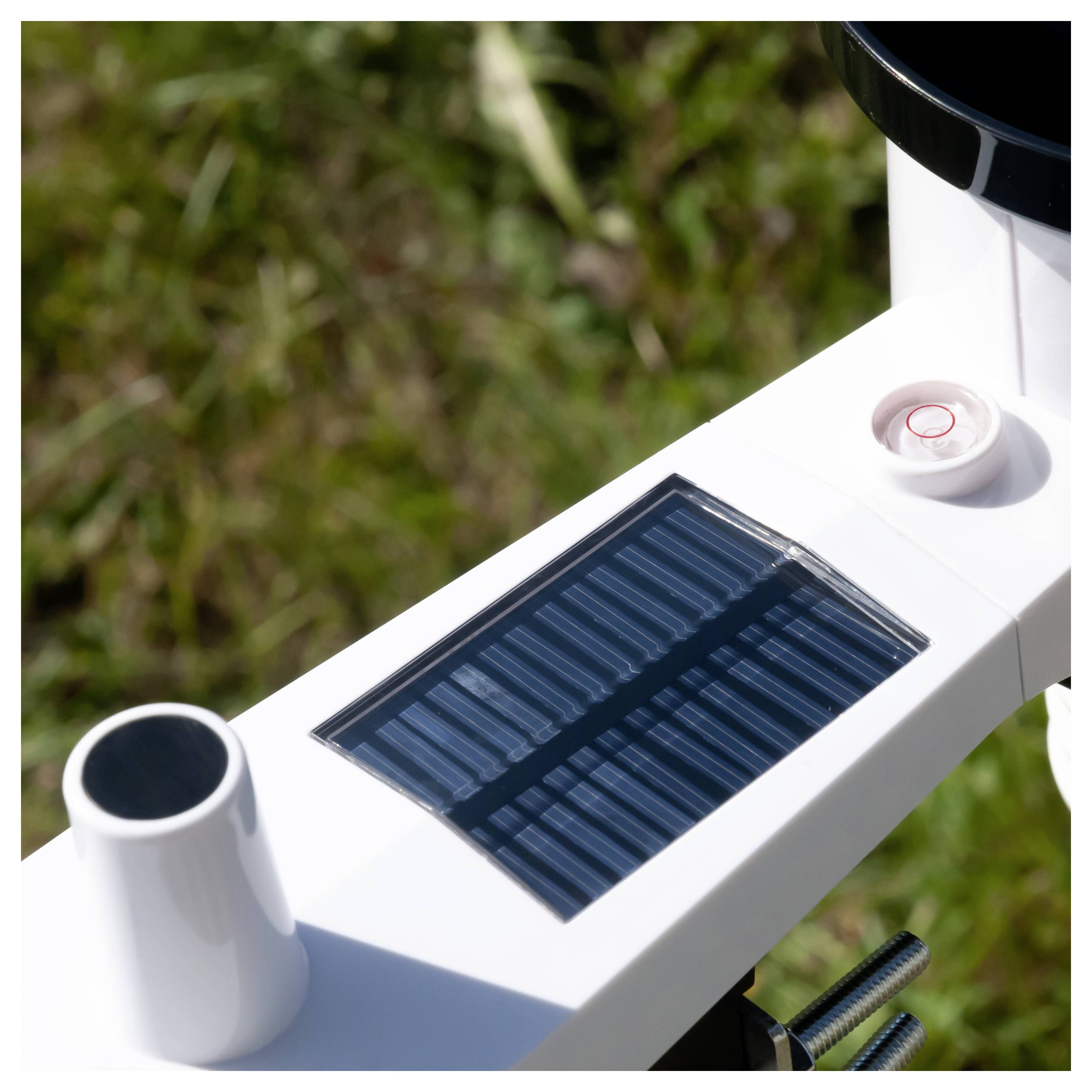 Gros plan du bras d'un drone avec un panneau solaire bleu, montré en extérieur sur un fond d'herbe.