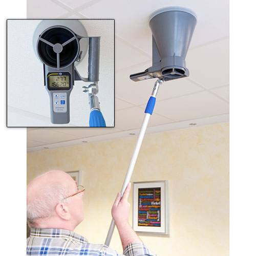 Un homme mesure la qualité de l'air intérieur au plafond à l'aide d'un appareil spécial fixé à une perche télescopique ; l'affichage indique « 167,2 ».