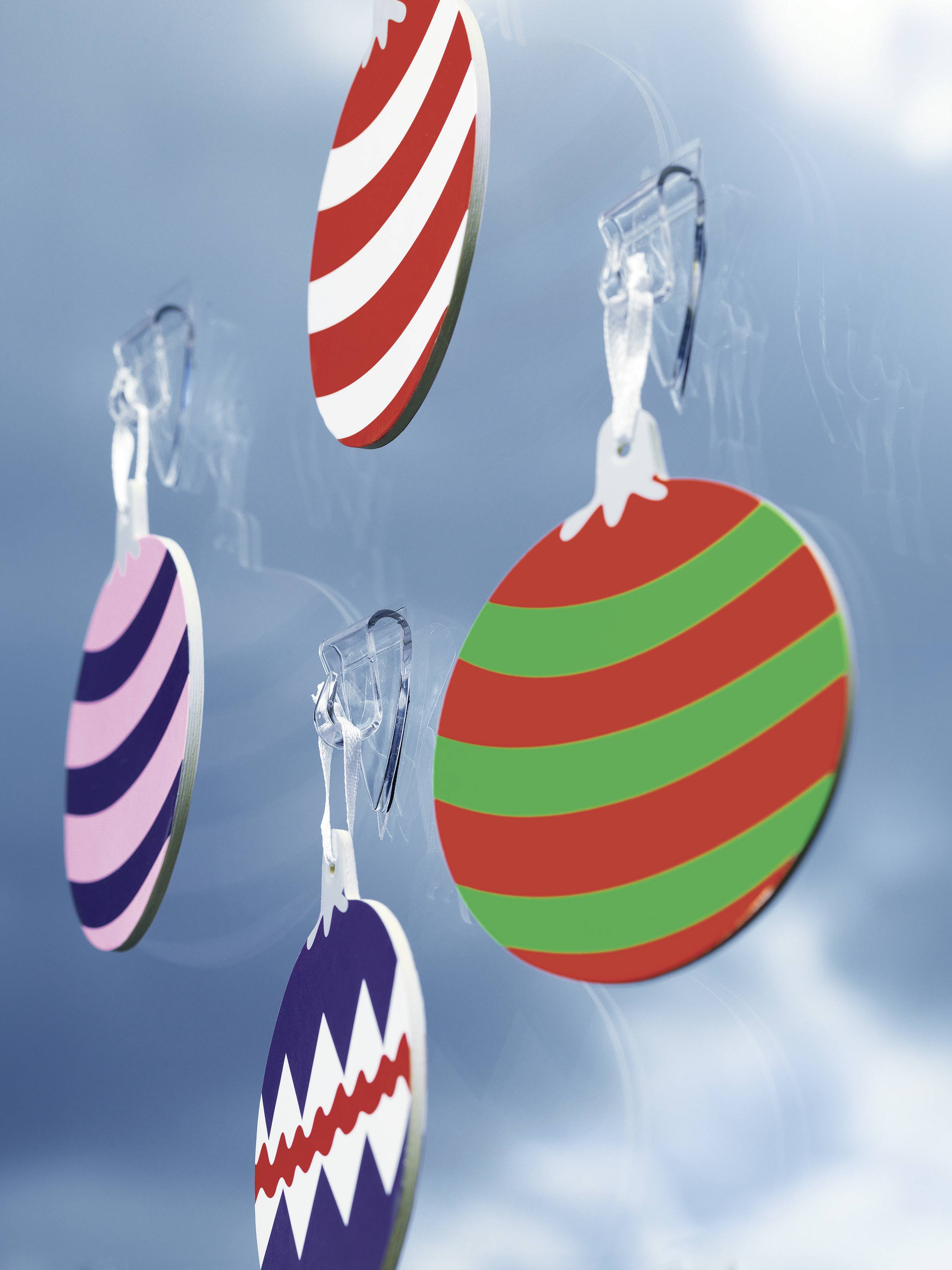 Des boules de Noël colorées, rayées et à motifs zigzag sont suspendues devant un ciel bleu.