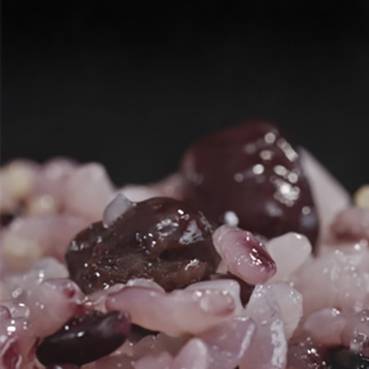 Gros plan sur du sel de mer rougeâtre et granuleux, mélangé à des grains de poivre noir.