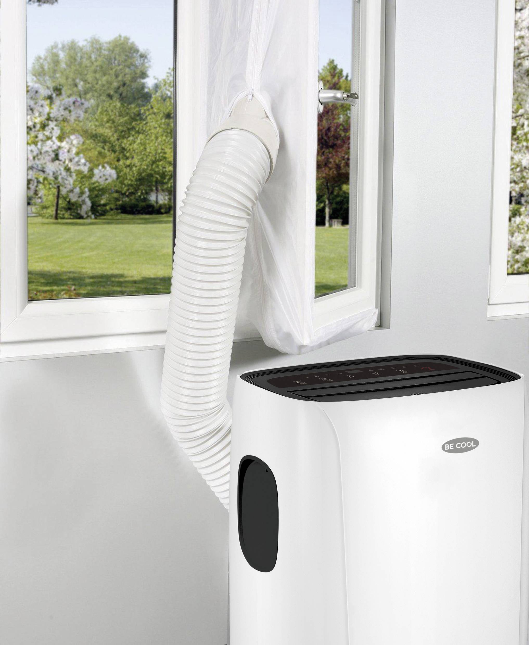 Climatiseur mobile avec un tuyau d'évacuation sortant par une fenêtre ouverte vers l'extérieur. L'arrière-plan montre un jardin ensoleillé.
