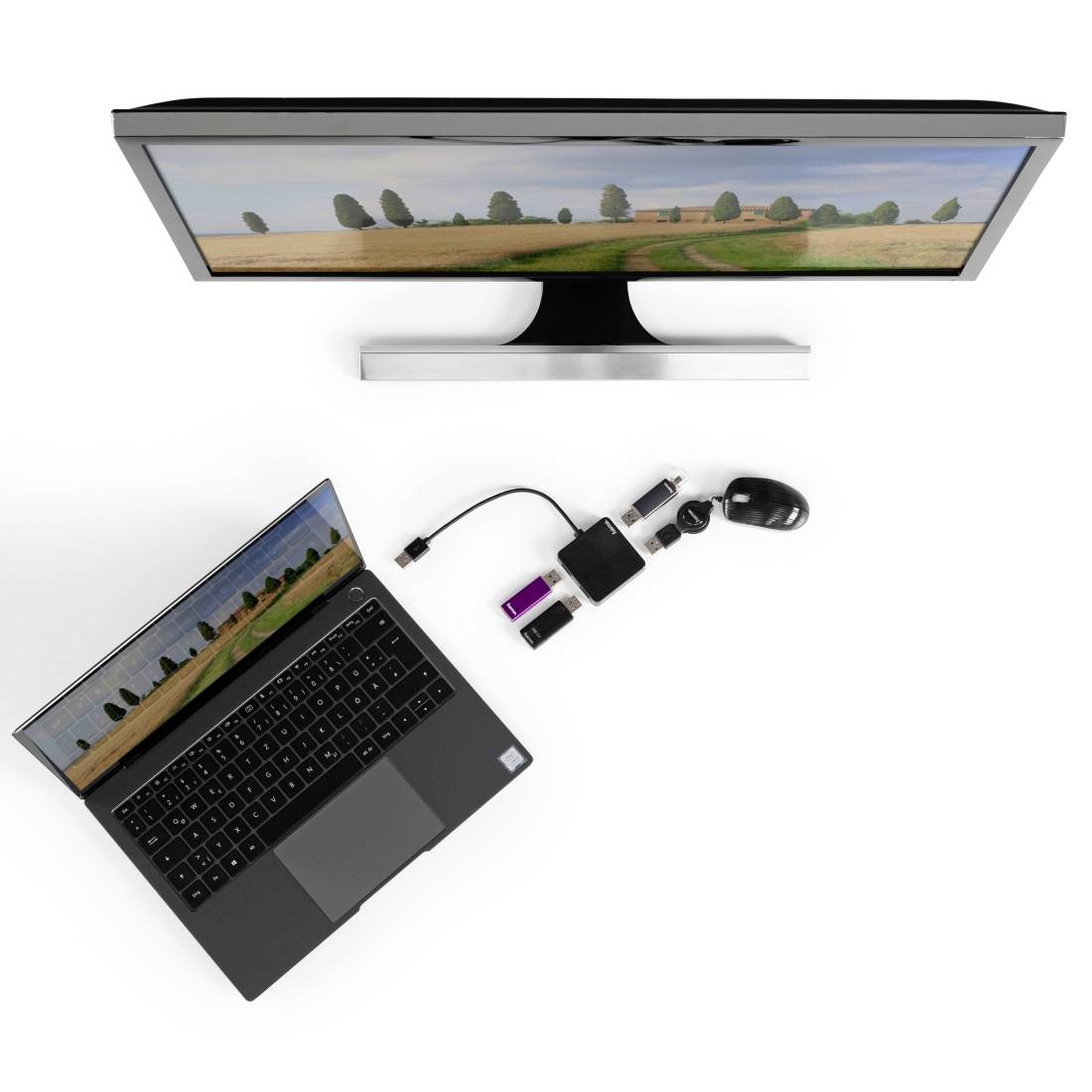Ordinateur portable et écran affichant la même image de paysage ; un hub USB relie l'ordinateur portable à la souris et à d'autres périphériques. Vue de dessus.