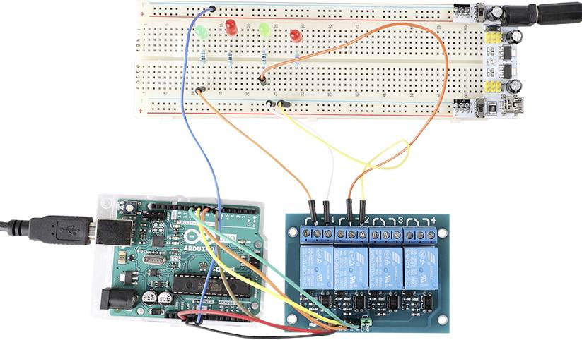 Contrôleur Arduino relié à une plaque d'expérimentation et un module de relais. Différents fils relient des LED et des composants.