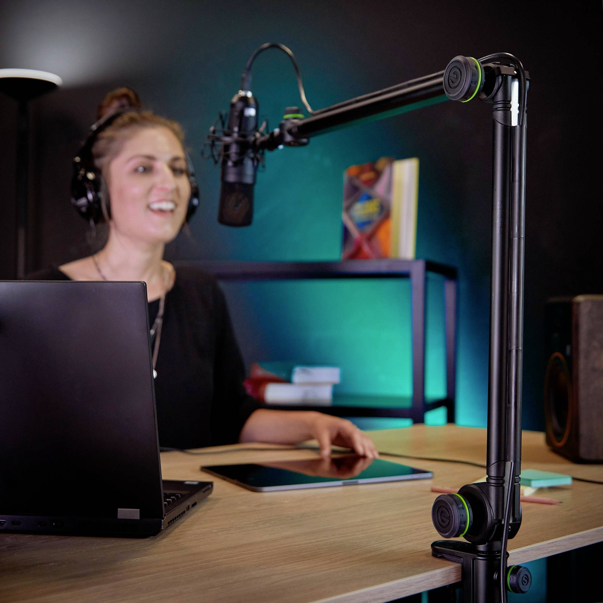 Une personne podcast à un bureau avec un microphone et un ordinateur portable, portant des écouteurs, entourée d'équipements techniques.