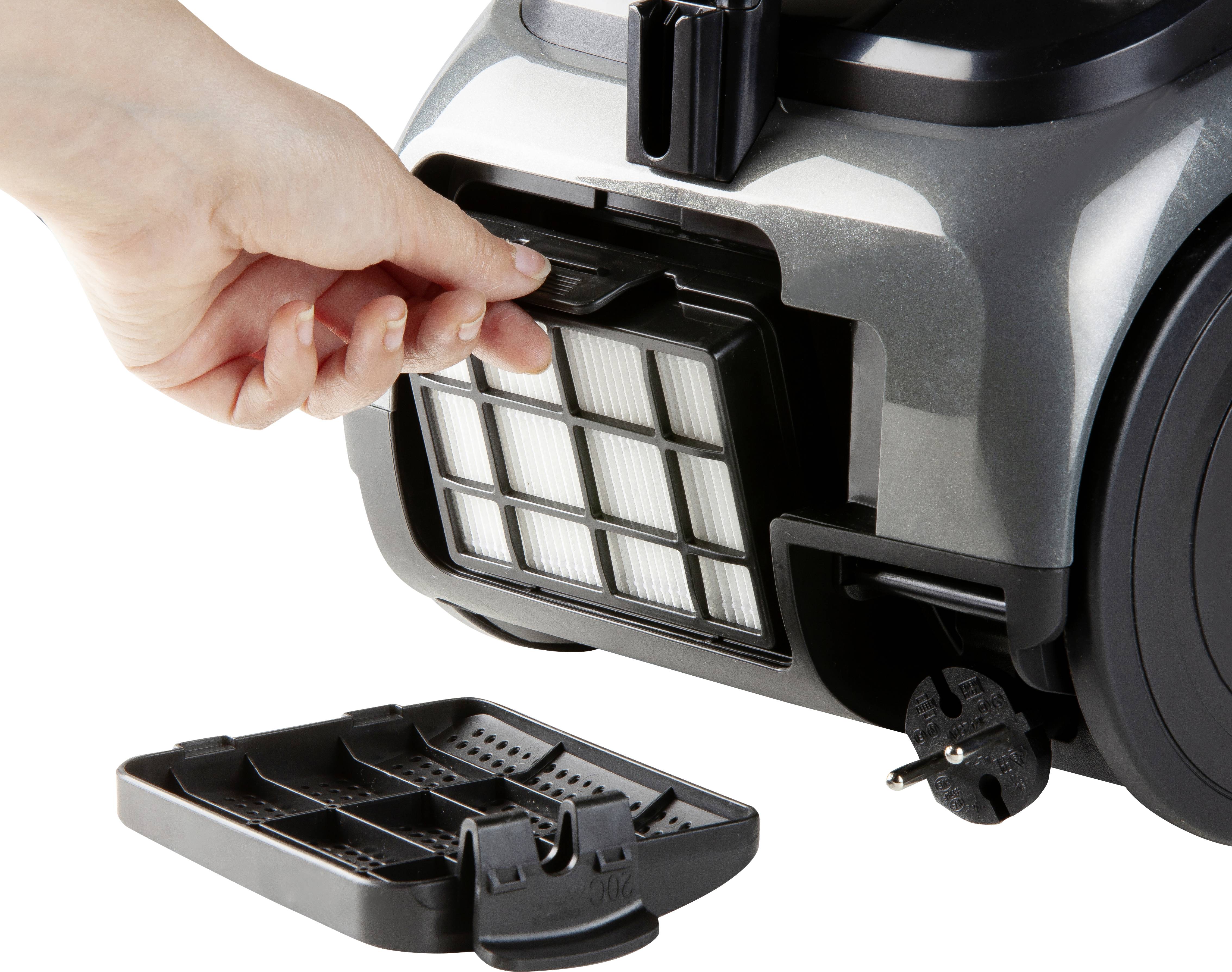 Une main ouvre le filtre HEPA d'un aspirateur, montrant le processus de remplacement.