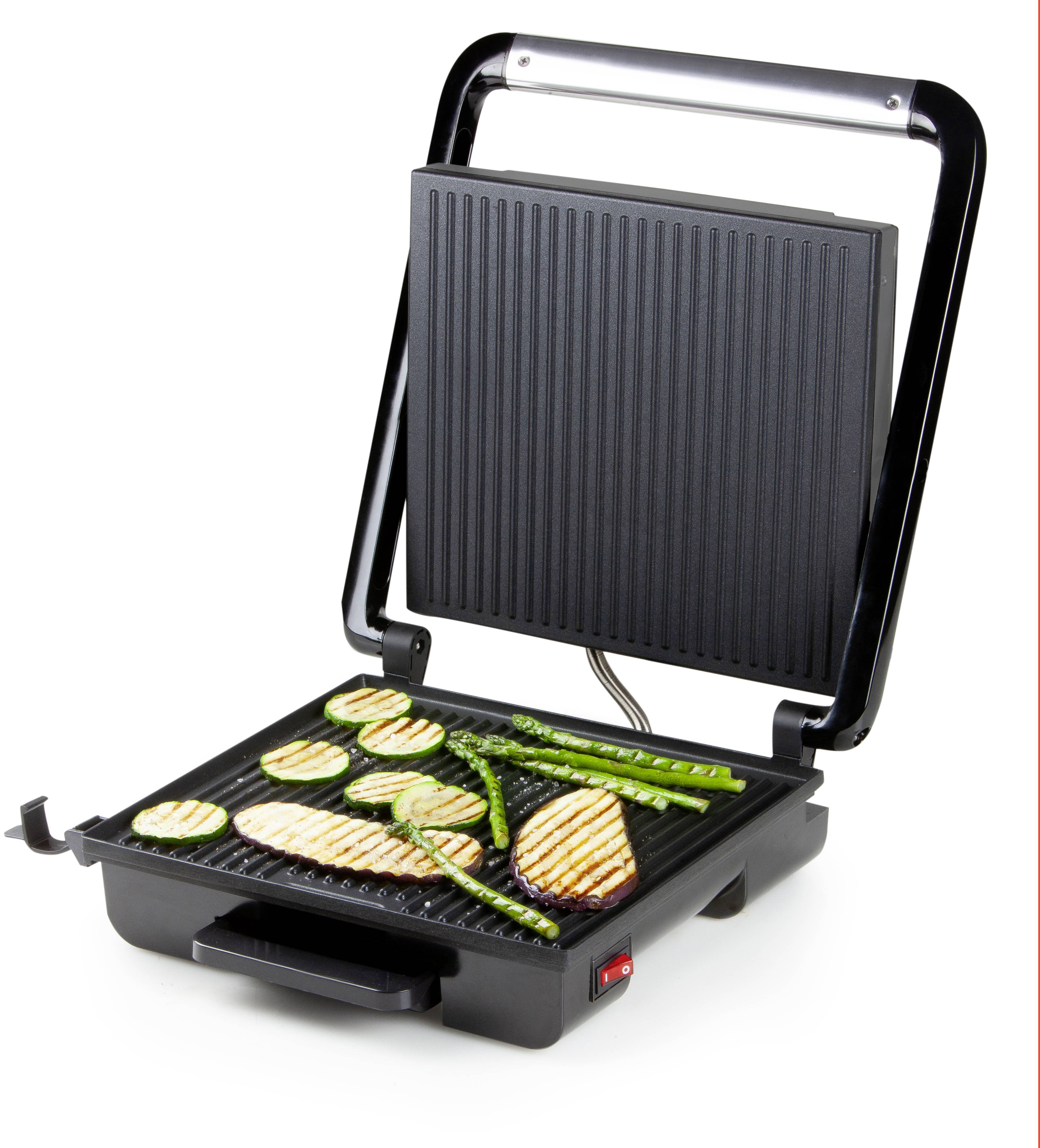 Un grill ouvert avec du poulet grillé, des courgettes et des asperges sur la surface de cuisson.